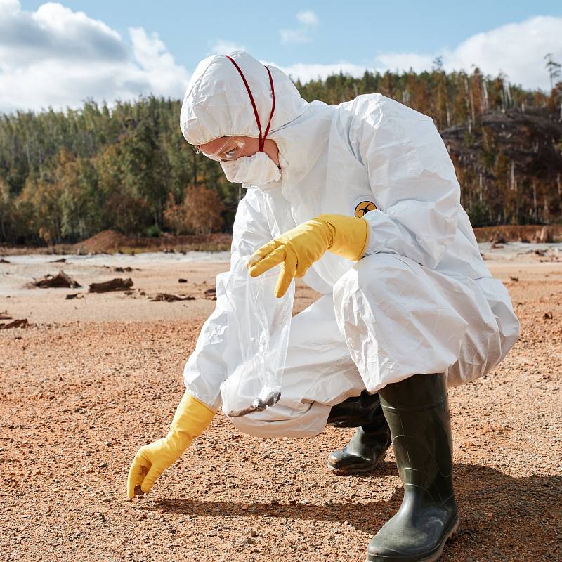 Fachkraft entnimmt Bodenprobe auf kontaminierter Fläche.