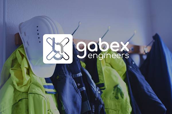 Schutzhelme und Arbeitsjacken hängen an einer Garderobe, darüber das Logo von gabex engineers.
