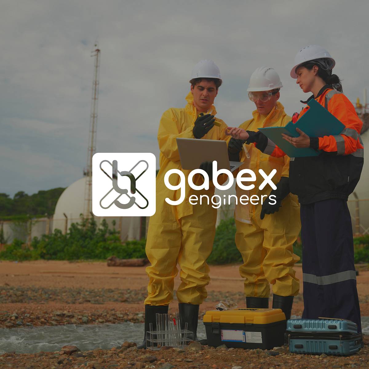 Drei Fachkräfte in Schutzanzügen und Helmen führen Umweltmessungen im Freien durch, analysieren Daten auf einem Laptop und dokumentieren Ergebnisse, davor das Logo von gabex engineers.