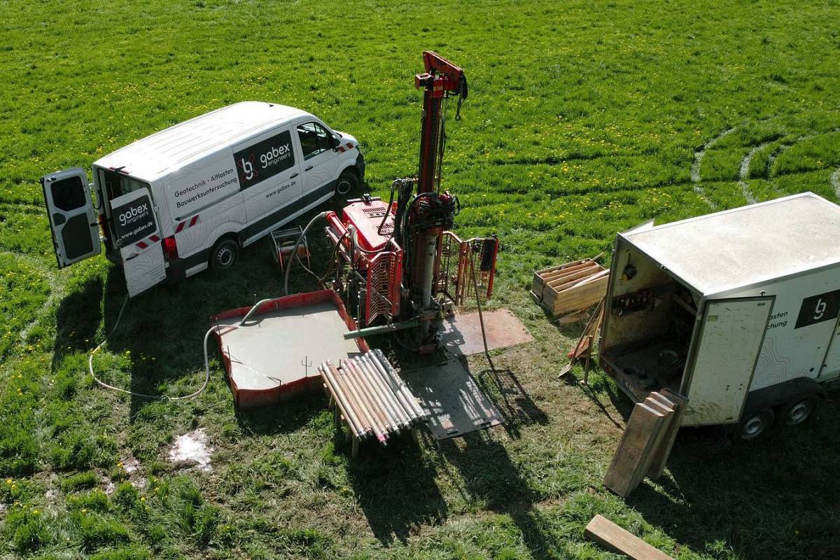 Geotechnische Bohrstelle auf einer Wiese mit mobilem Bohrgerät, Bohrgestänge sowie Fahrzeugen und Ausrüstung von gabex engineers.