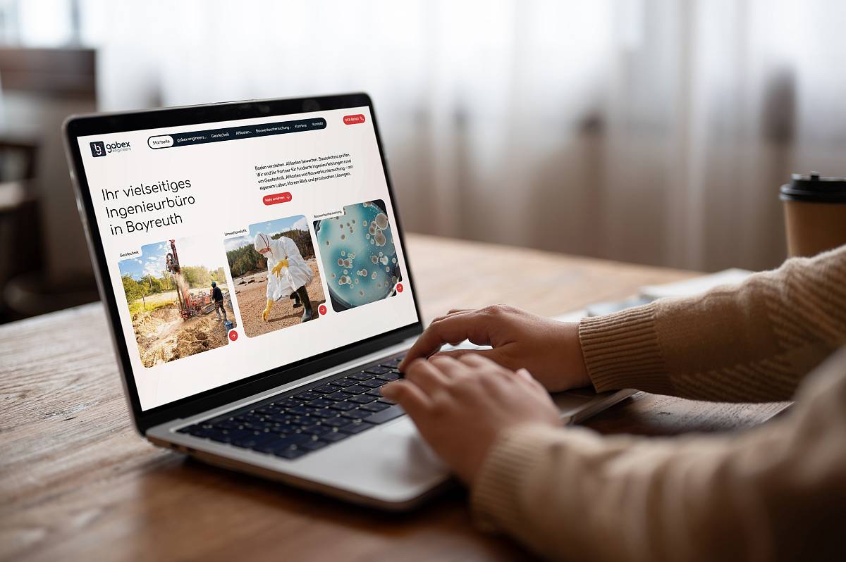 Person arbeitet an einem Laptop, auf dem die Website von gabex engineers mit den Leistungsbereichen Geotechnik, Umwelttechnik und Bauwerksuntersuchung geöffnet ist.