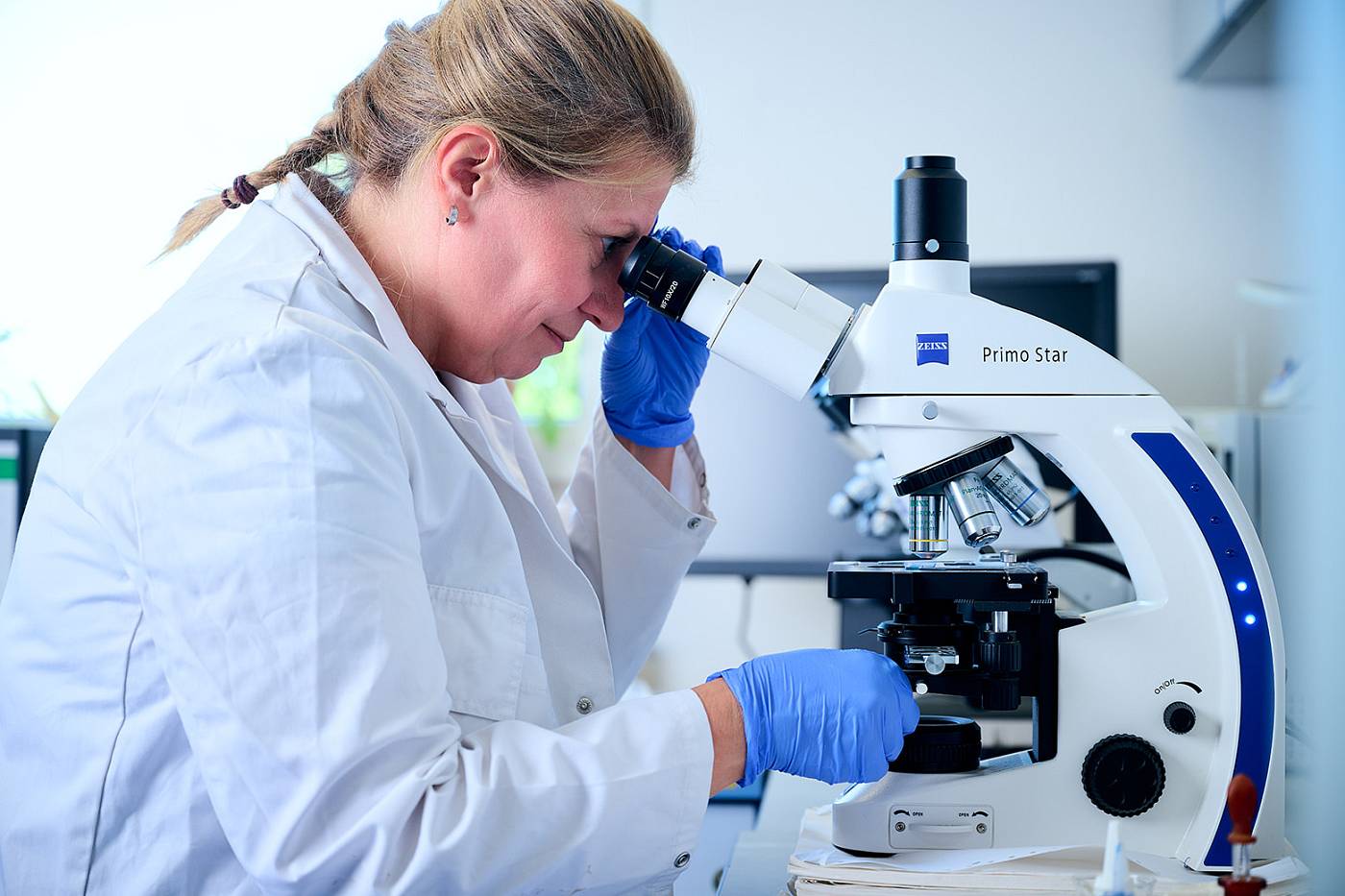 Mitarbeiterin von gabex engineers untersucht eine Probe mit einem Mikroskop im Labor.