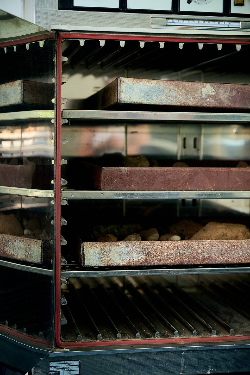 Geöffneter Probenschrank mit Gesteins- und Bodenproben zur Trocknung und Untersuchung im Labor.