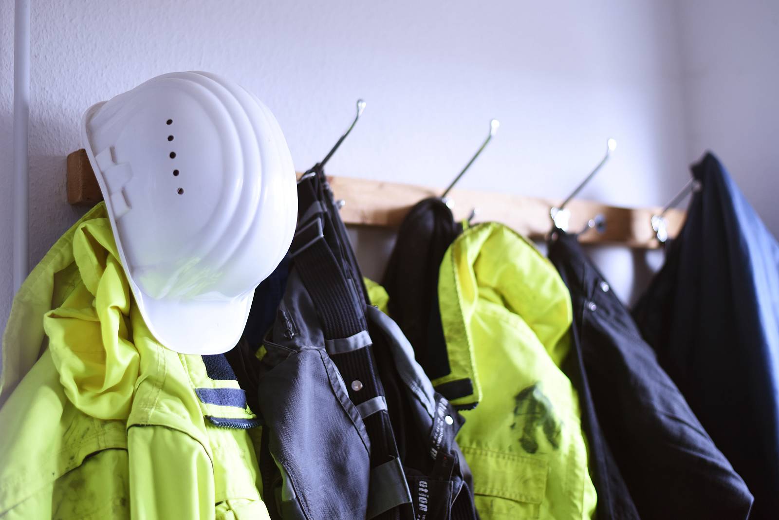 Ein weißer Schutzhelm und Arbeitsjacken an einer Gaderobe