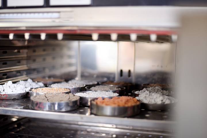 Bodenproben in Metallschalen werden in einem Laborofen getrocknet.