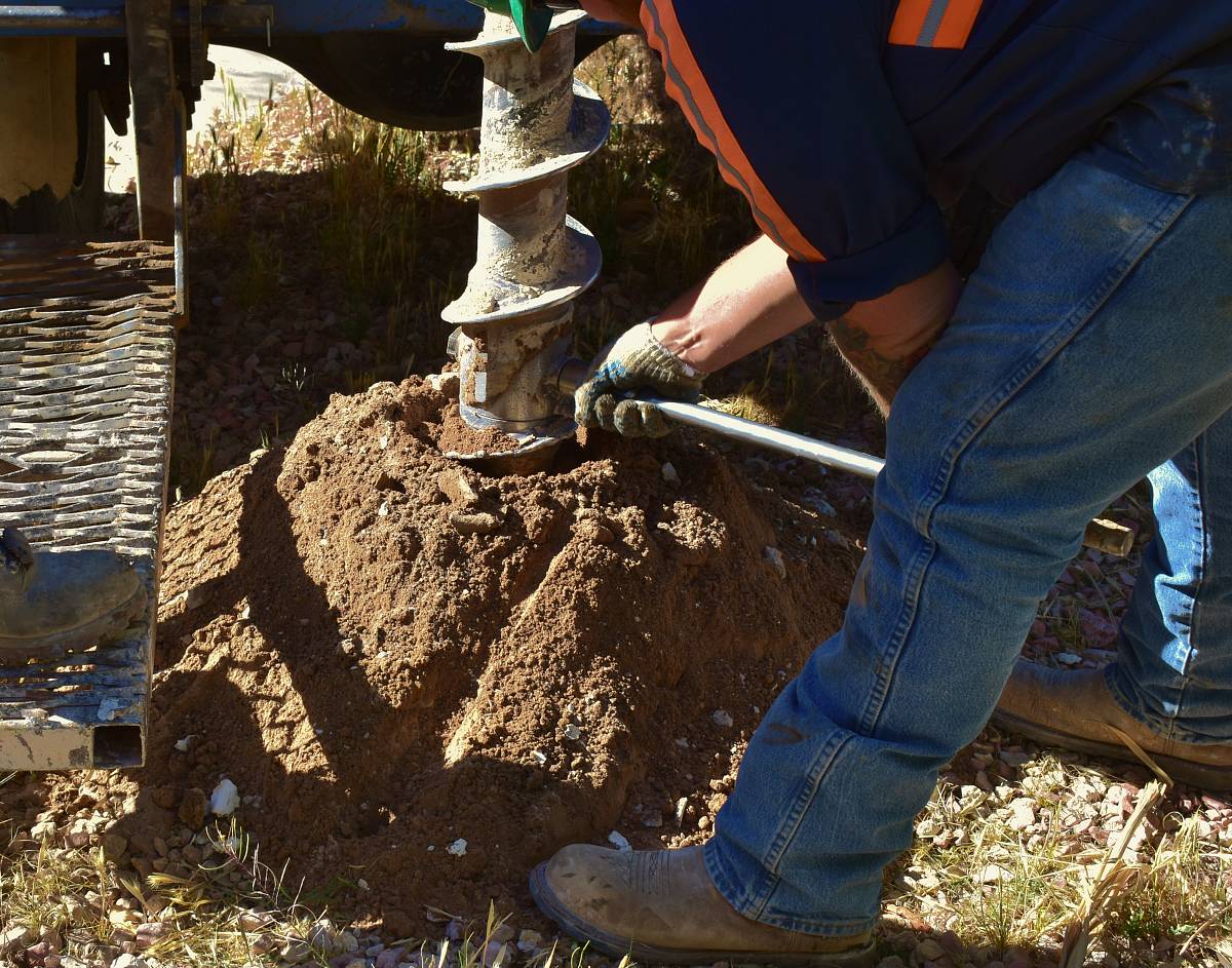 Arbeiter entnimmt Bodenprobe mit einem Bohrgerät auf einer Baustelle.