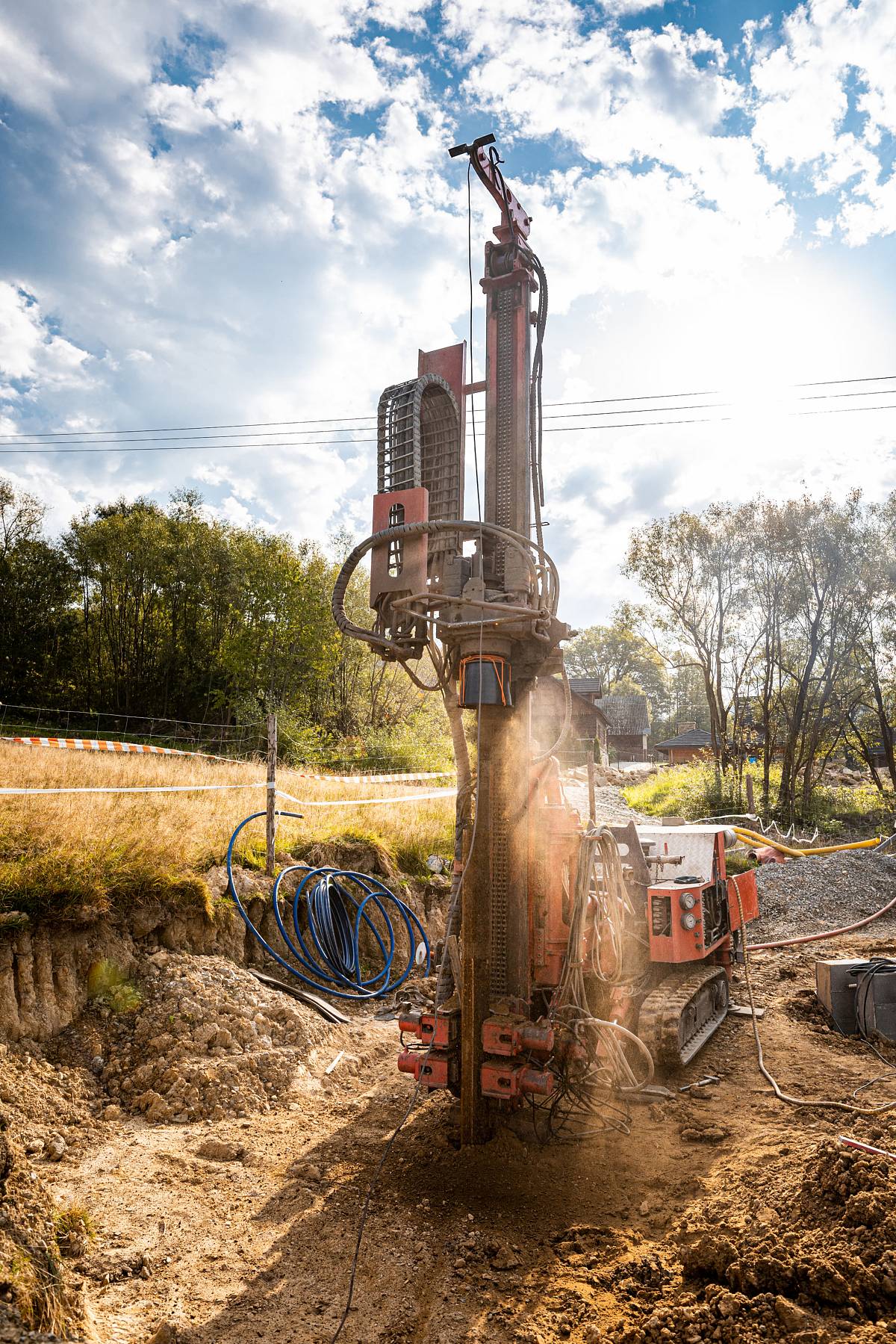 Großes Bohrgerät im Einsatz auf einer Baustelle bei sonnigem Wetter mit Erdreich im Vordergrund.