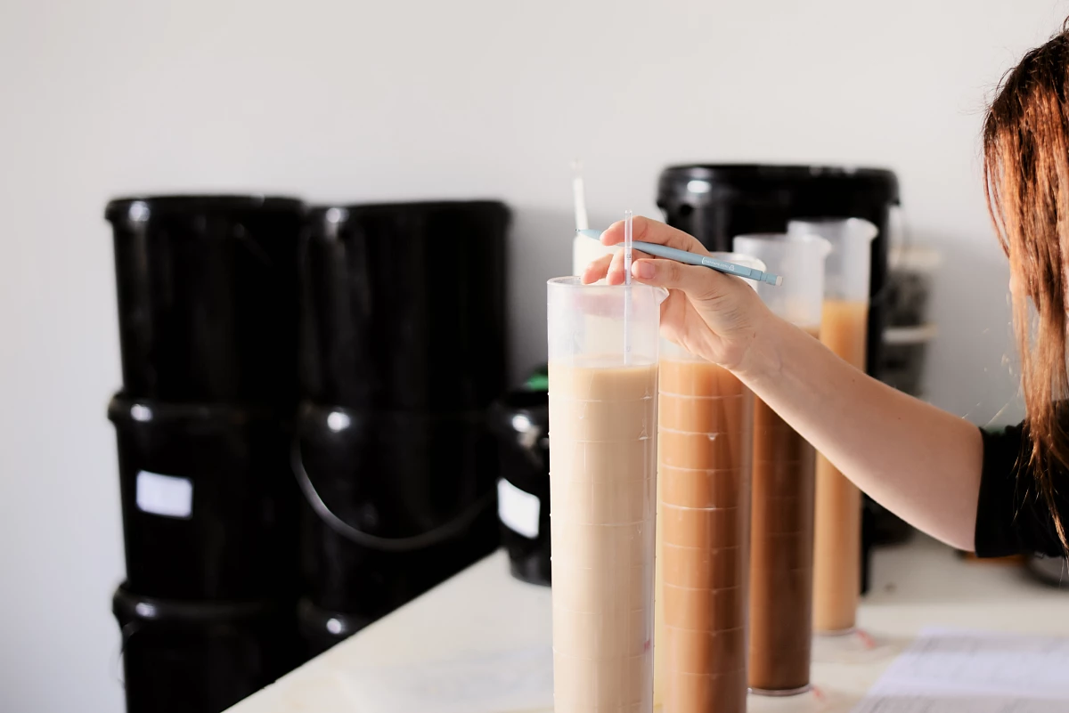 Laborarbeit mit Messzylindern, gefüllt mit Bodenproben in unterschiedlichen Schichten und Farben.