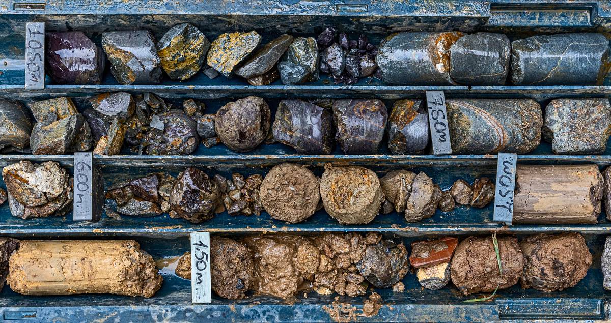 Verschiedene Gesteins- und Bodenproben in einer Bohrkernbox, sortiert nach Tiefe und Schicht.