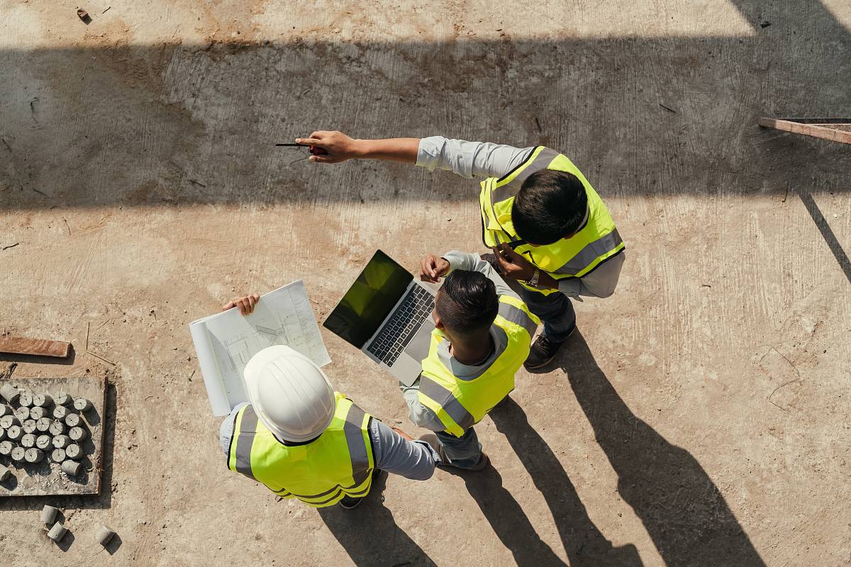 Geotechniker auf der Baustelle besprechen Bohrkerne, Bodenproben und Baugrundpläne zur Analyse des Untergrunds.