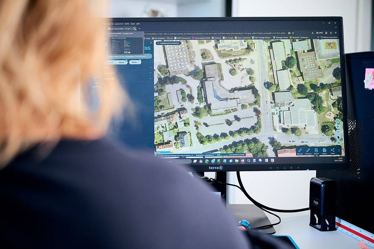 Mitarbeiterin von gabex engineers betrachtet eine Luftaufnahme zur Planung und Analyse am Computer.