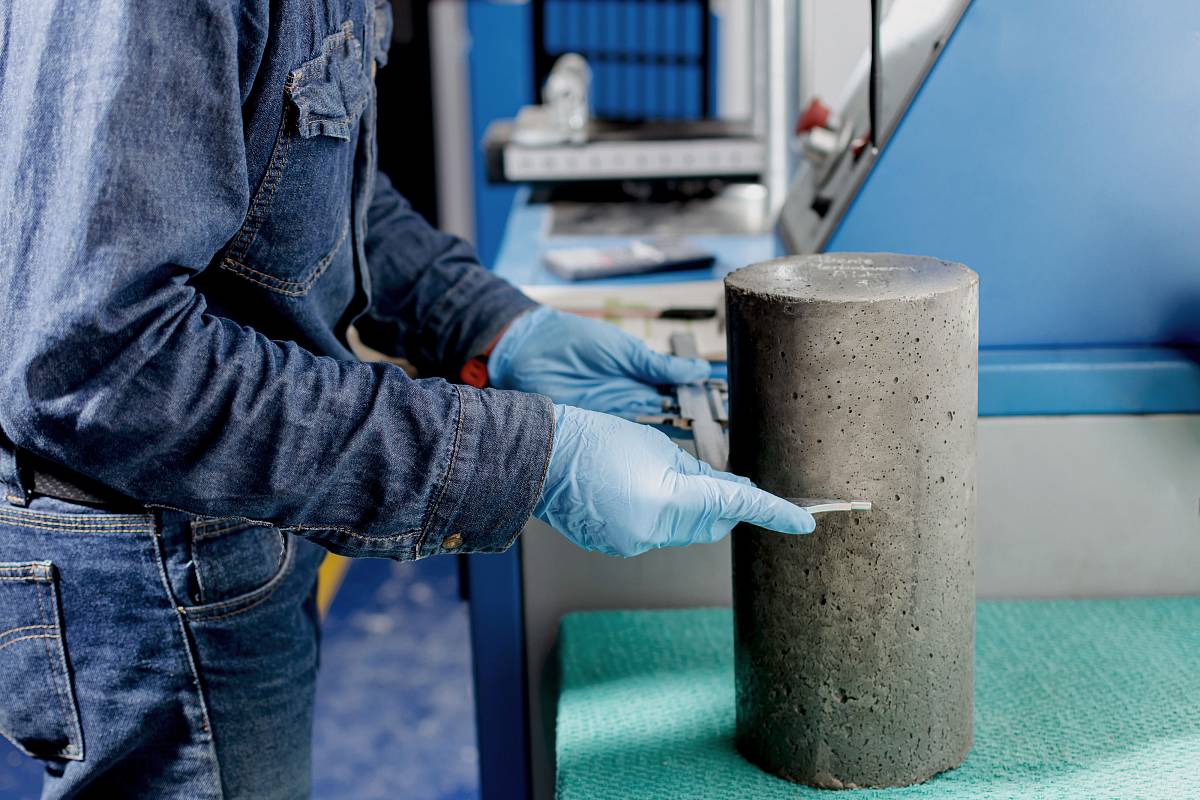 Ingenieur misst einen zylindrischen Betonprobekörper im Labor zur Analyse der Materialeigenschaften.