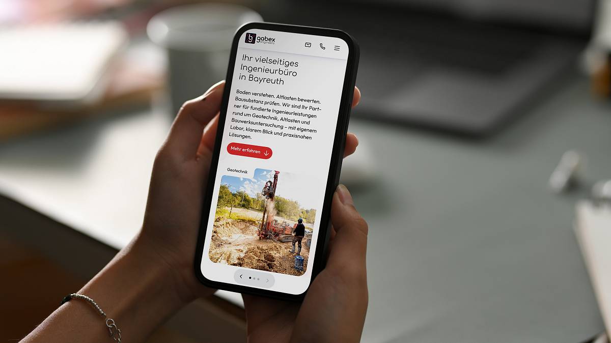 Hände einer Person, die ein Smartphone halten, auf der die Startseite von gabex engineers zu sehen ist.