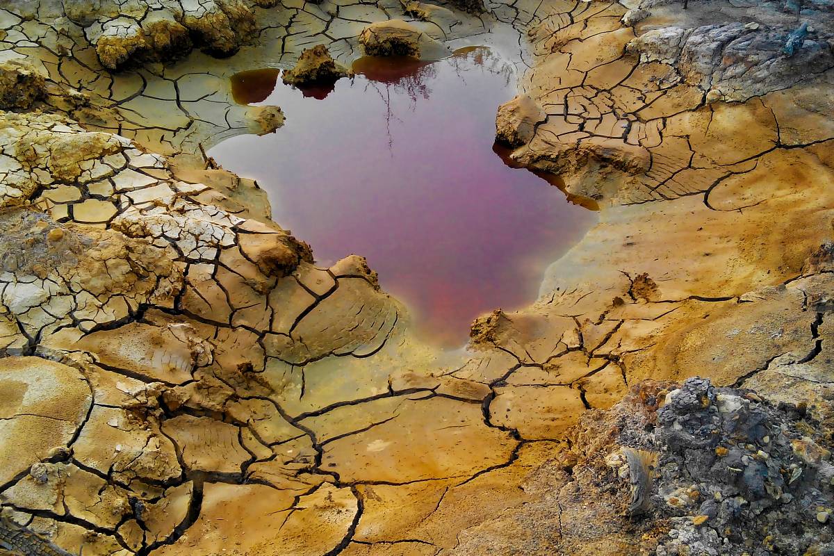 Roter Tümpel auf rissigem, kontaminiertem Boden als Zeichen von Umweltverschmutzung.