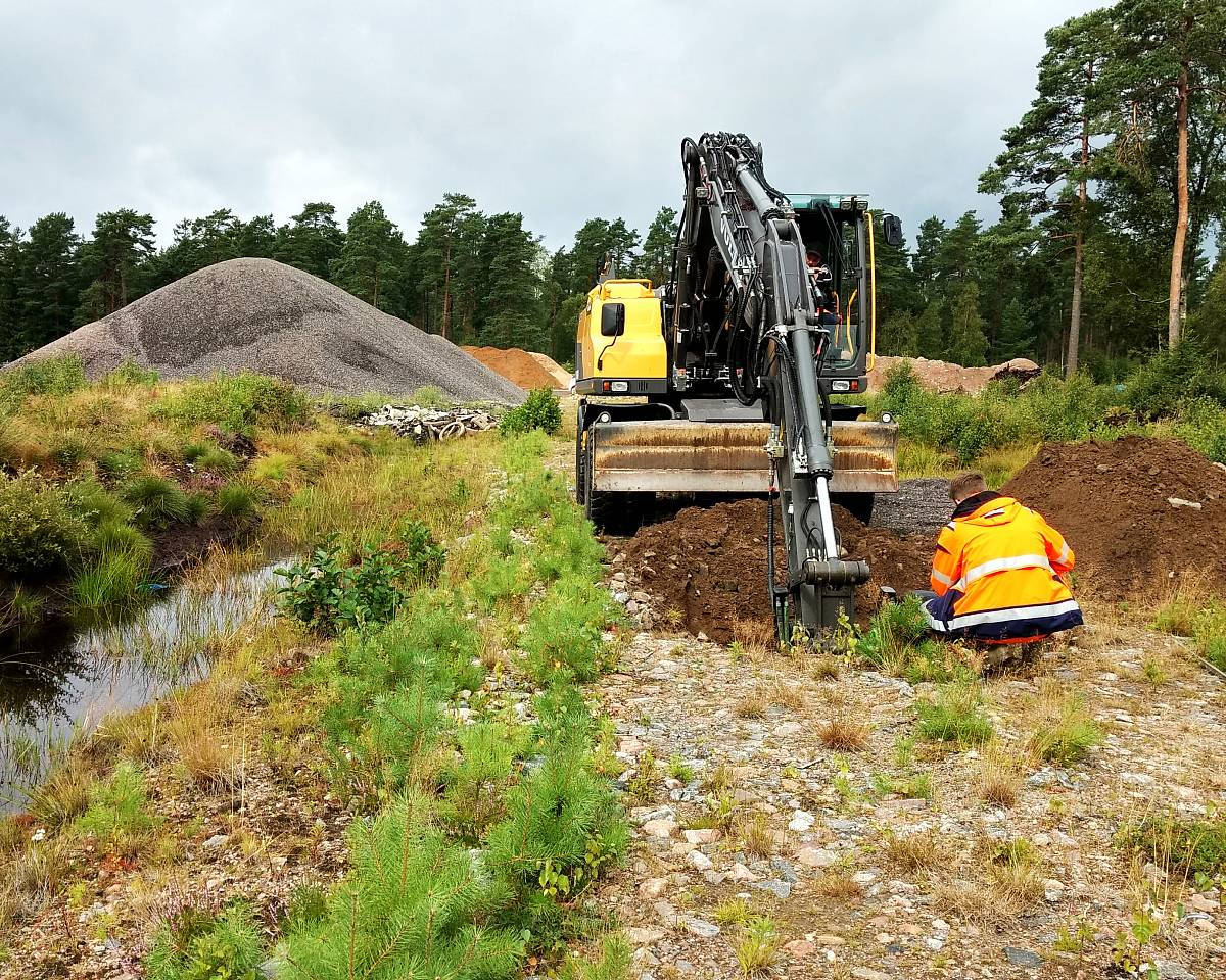 Bagger und Ingenieur bei der Aushubsanierung und Bodenuntersuchung auf einer Baustelle im Gelände.