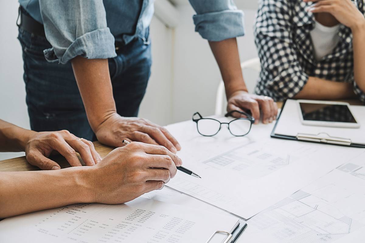 Ingenieure besprechen Baupläne und Messergebnisse am Schreibtisch zur Projektplanung.