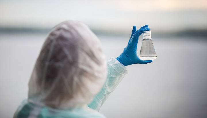 Fachperson überprüft Wasserprobe im Laborgefäß zur Beurteilung der Wasserqualität.