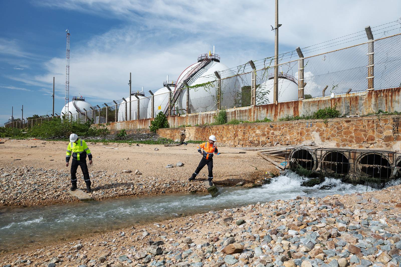 Fachkräfte entnehmen Wasserproben an einem Industrieareal zur Umweltuntersuchung.