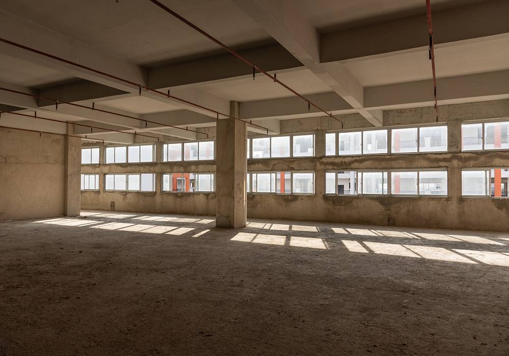 Leerer Rohbau mit freiliegenden Betonwänden und unbeschichtetem Boden zur Vorbereitung einer Bauwerksuntersuchung und Schadstoffbewertung im Bestand.