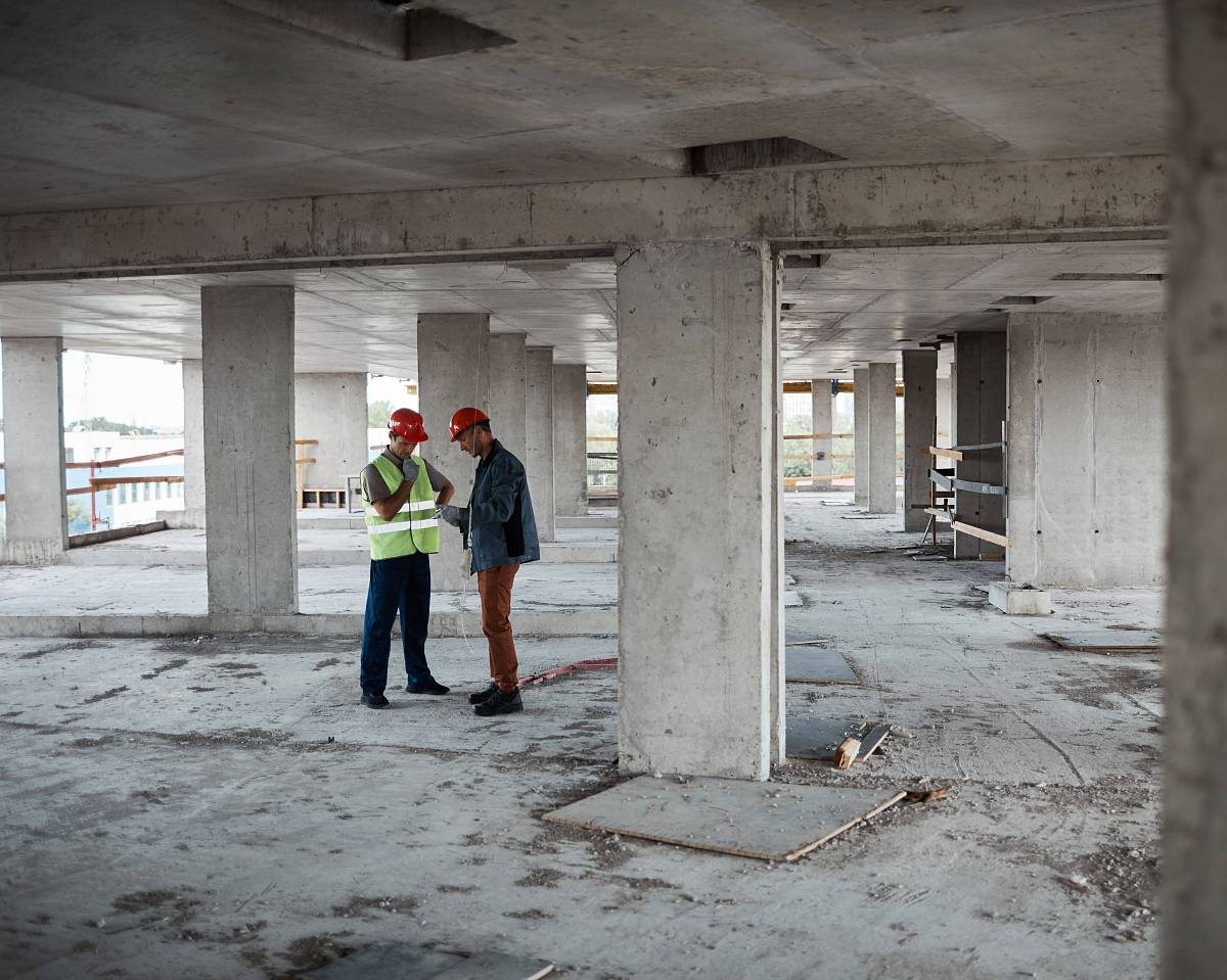 Zwei Bauingenieure begutachten die Bausubstanz eines Rohbaus, um Schadstoffe und strukturelle Eigenschaften im Rahmen einer Bauwerksuntersuchung zu bewerten.
