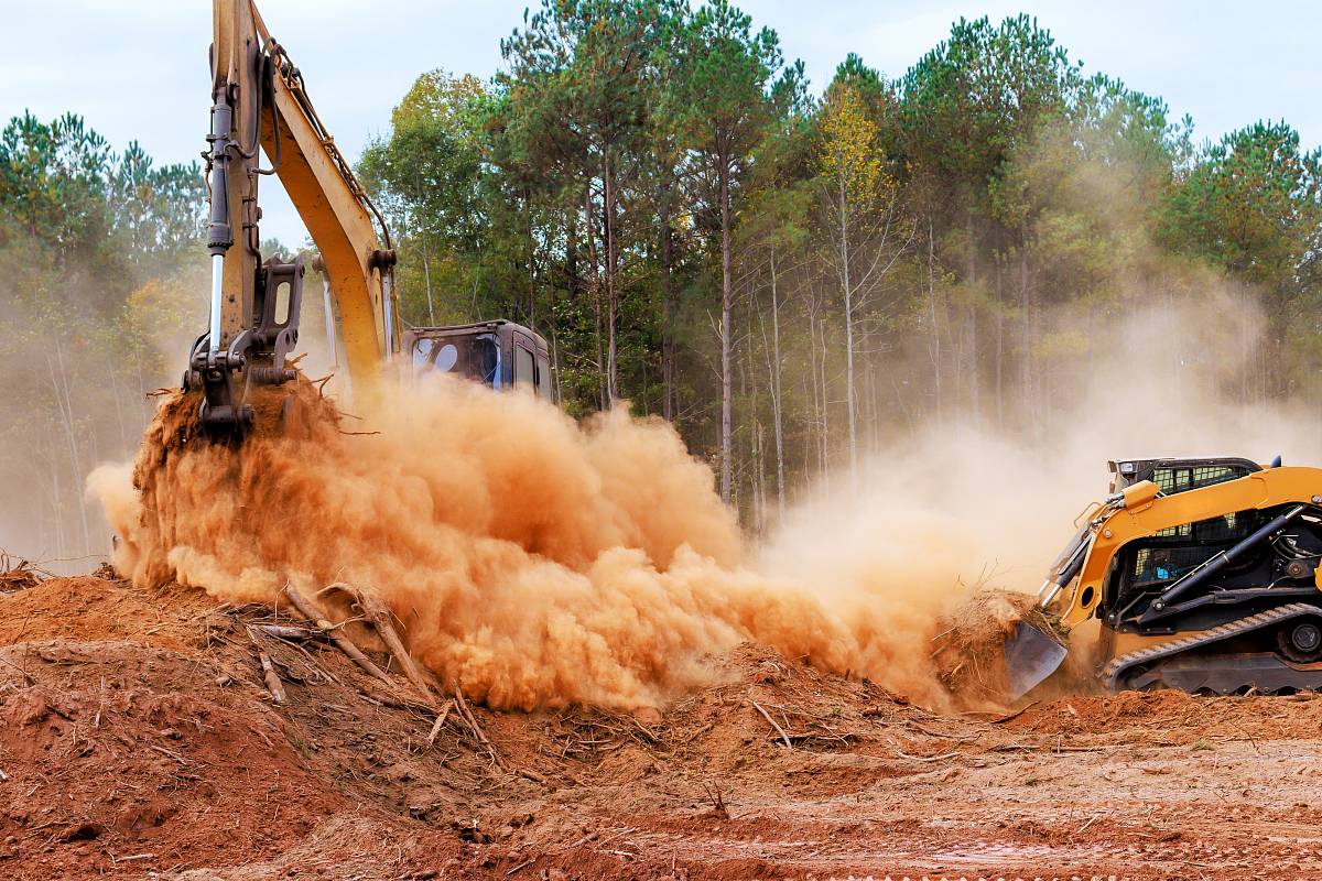 Bagger und Radlader beim Bewegen von Erdaushub auf einer Baustelle.