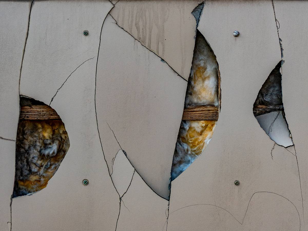 Aufgebrochene Wand mit freiliegender Mineralwolldämmung – Untersuchung von Baustoffen auf Schadstoffe und Materialalterung.